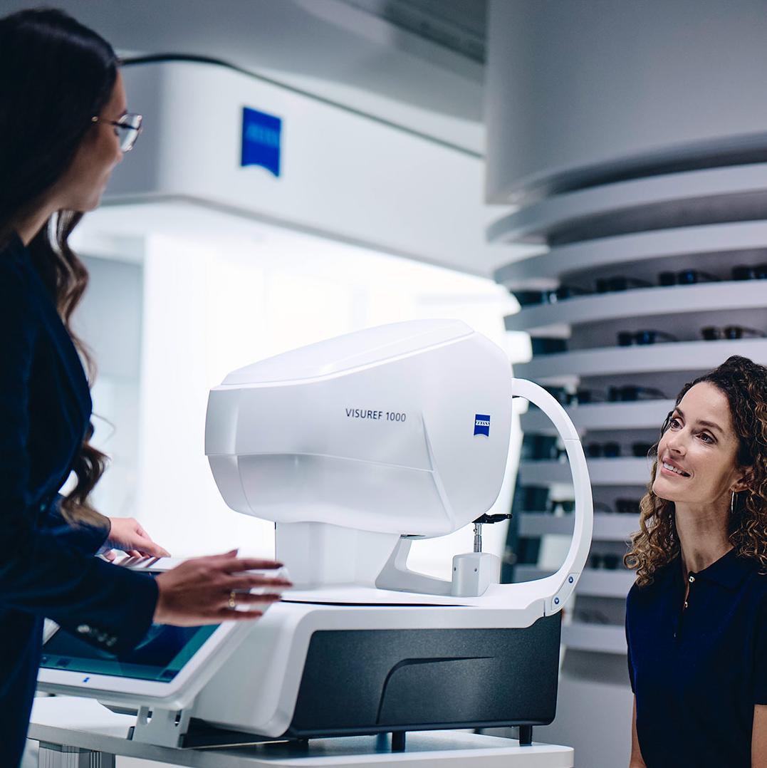 En kvinde sidder foran ZEISS VISUREF 1000 og ser på en kvindelig optiker.