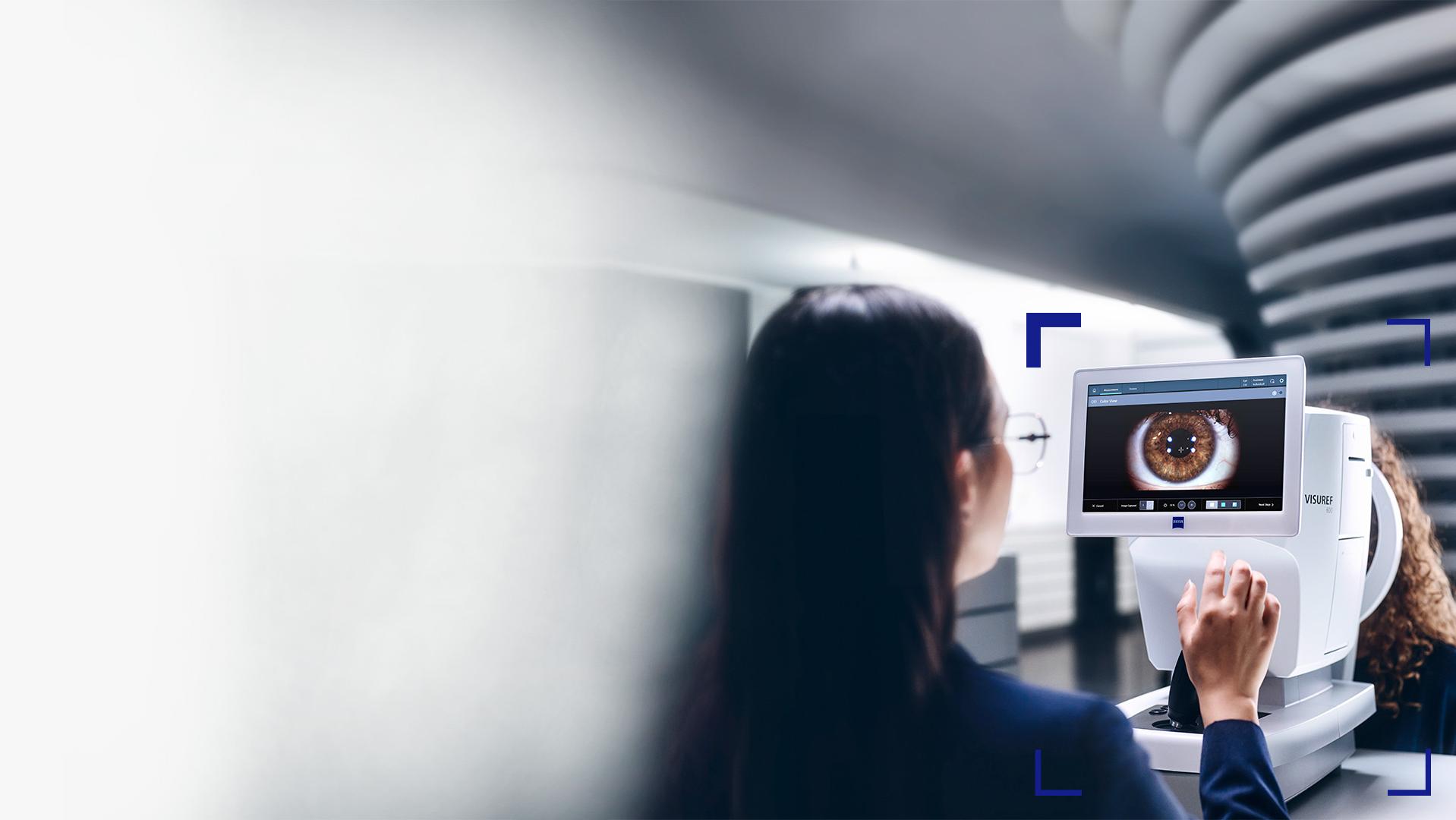 En kvindelig optiker ser på skærmen på ZEISS VISUREF 600, der viser et billede af et øje.