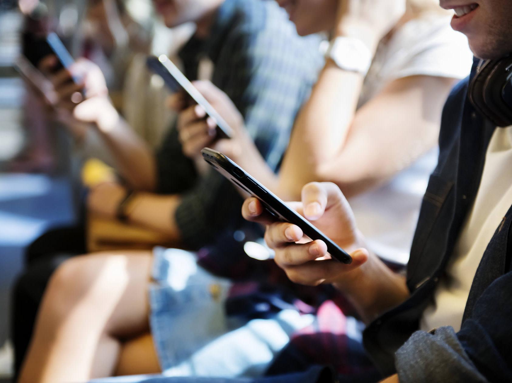 Smartphones udsender store mængder blåt lys. På billedet ses flere mennesker der ser på deres smartphones. 