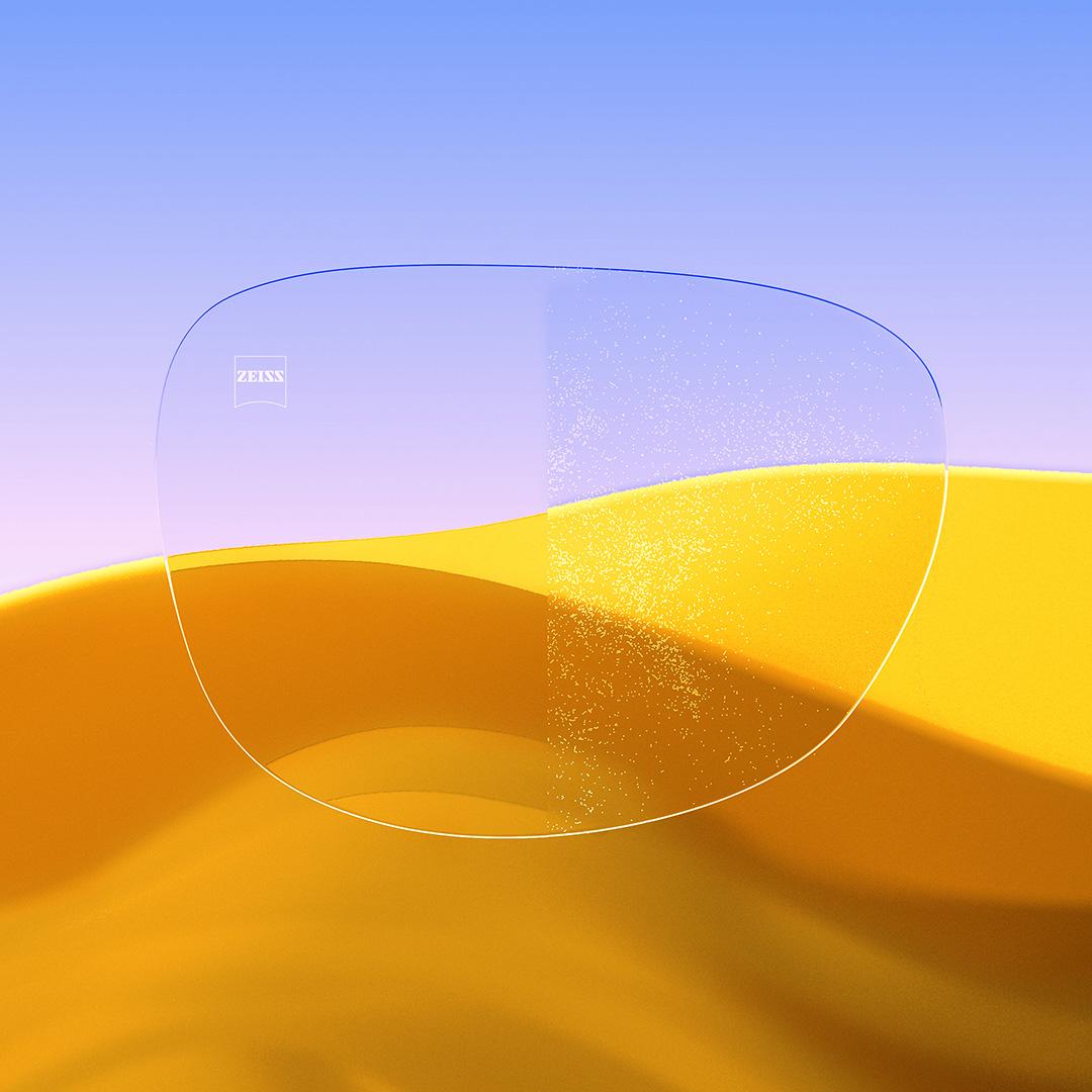 Et delt brilleglas med den ene side klar og ren med ZEISS DuraVision Gold UV og den anden side med støv på glasset.