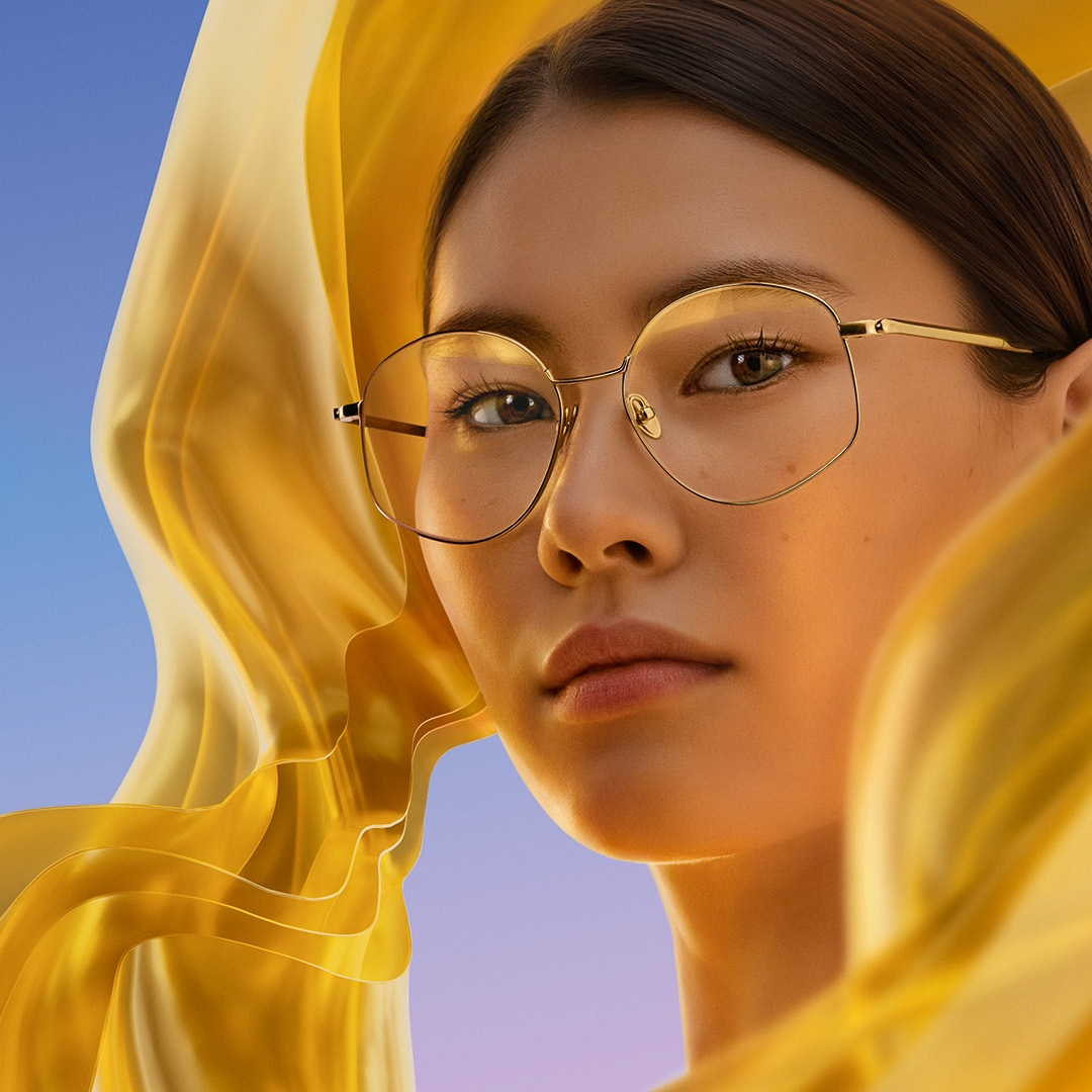 Kvinde der bærer briller med ZEISS DuraVision Gold UV anti-refleksglas, hvor den subtile gyldne refleks vises på glasset.