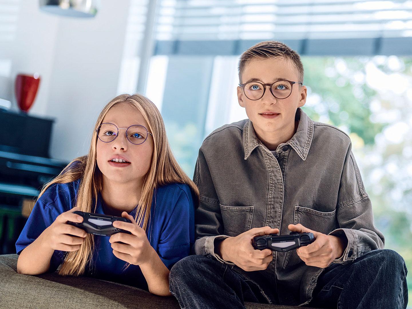 En teenage-pige og -dreng spiller videospil med konsol.