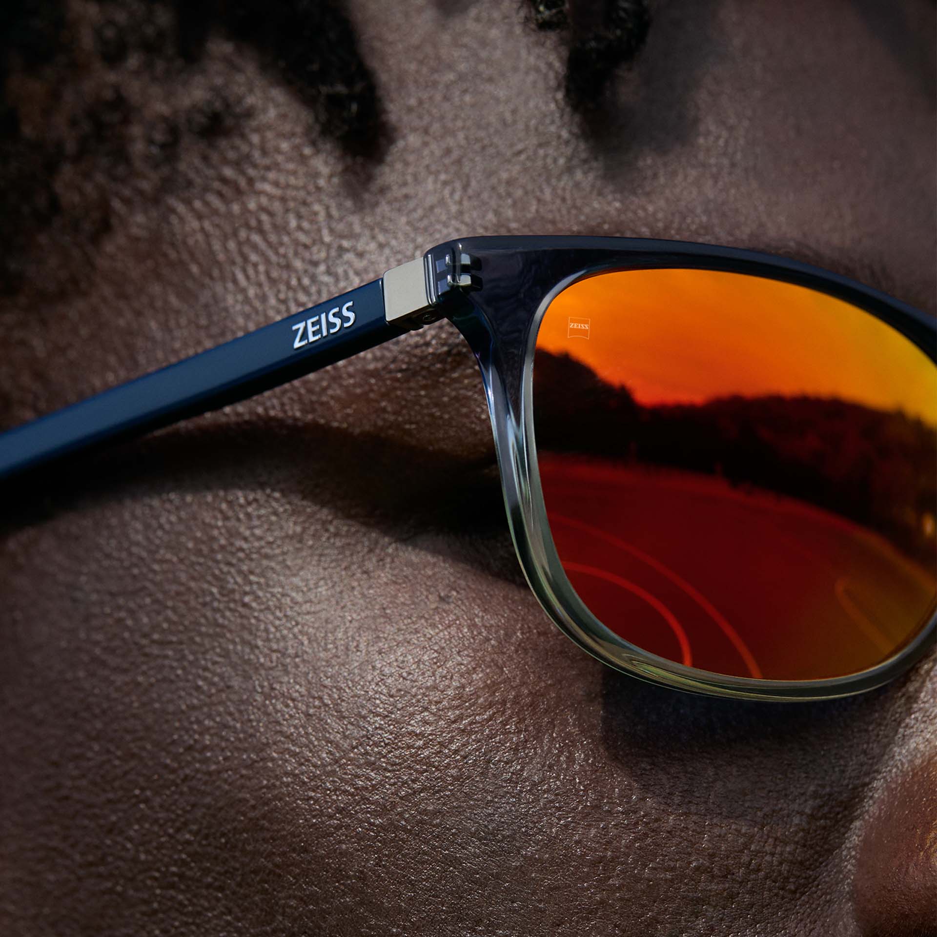 Nærbillede af en mand, der bruger ZEISS-briller med ZEISS DuraVision Mirror UV-solbrille-coating i orange farve.
