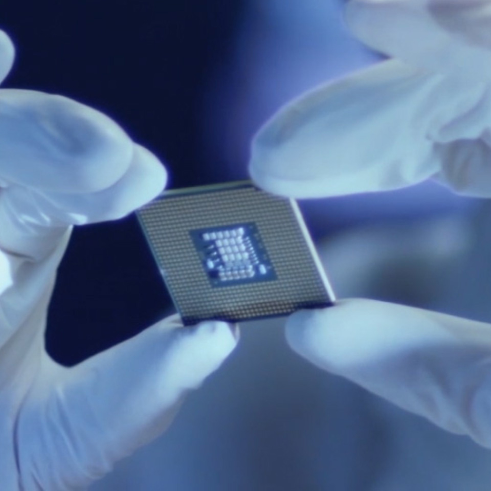 Et billede af en mikrochip, som en person holder med laboratoriehandsker på. 