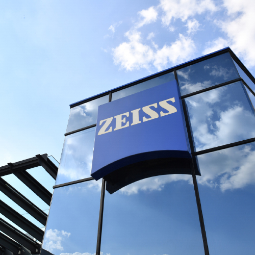 Et billede af en moderne glasbygning med et stort ZEISS-logo på. 