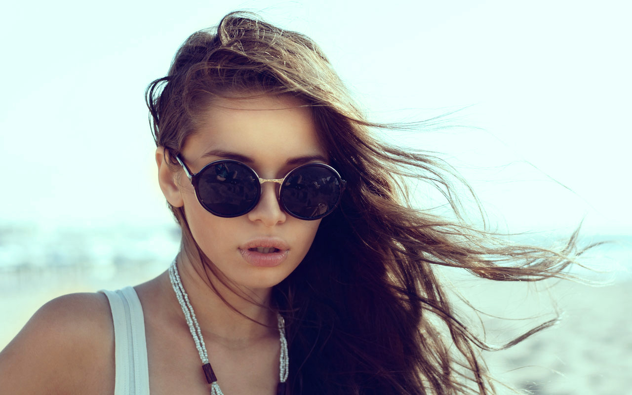 pige med solbriller ved strand