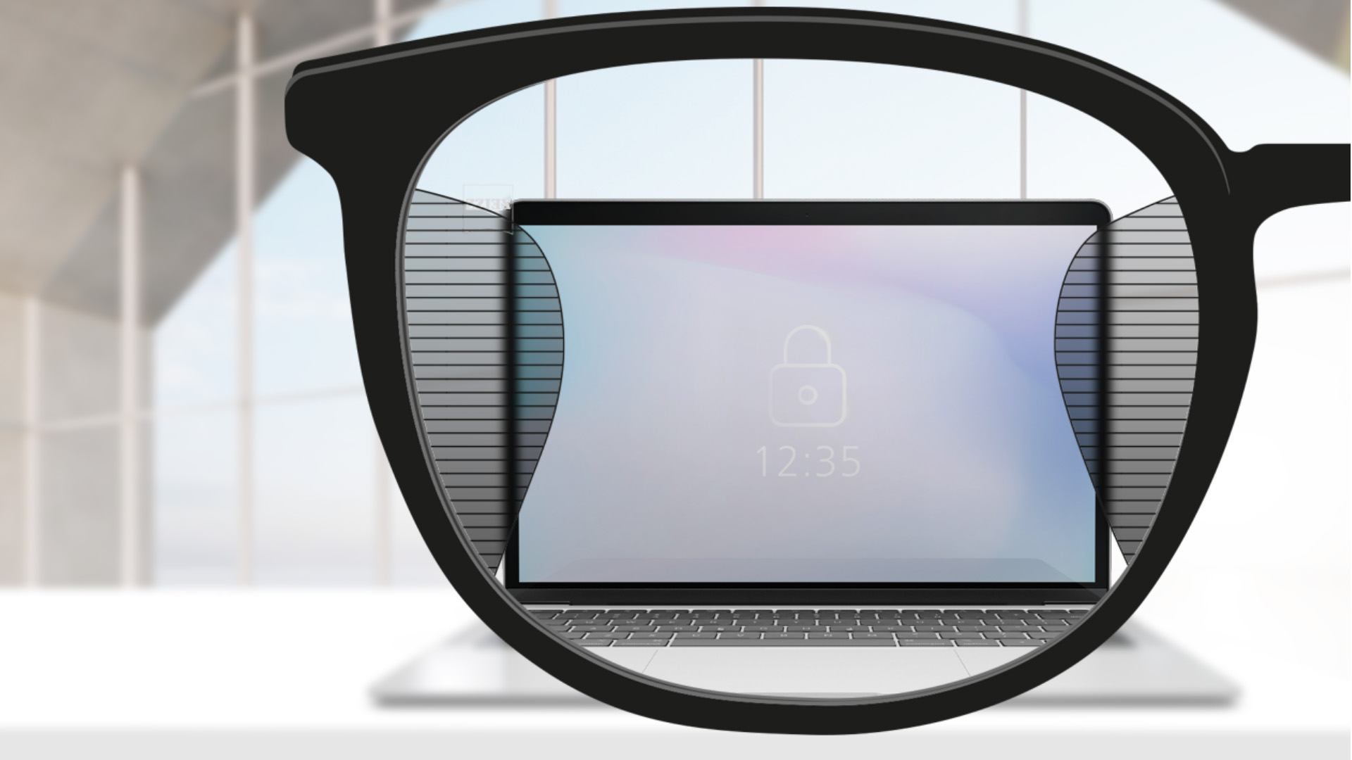 Et udsnit af et billede med ZEISS Office brilleglas med en computerskærm i midten af brilleglasset og smalle slørede pletter til venstre og højre.