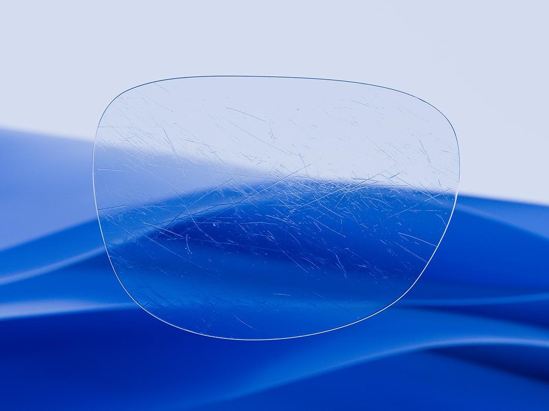 Delt illustration, der viser et ZEISS brilleglas i den ende side, som kan genkendes på dets klarhed og renhed, hvorimod den anden side viser et ridset konventionelt brilleglas. De fremhæver forskellen på holdbarheden. 