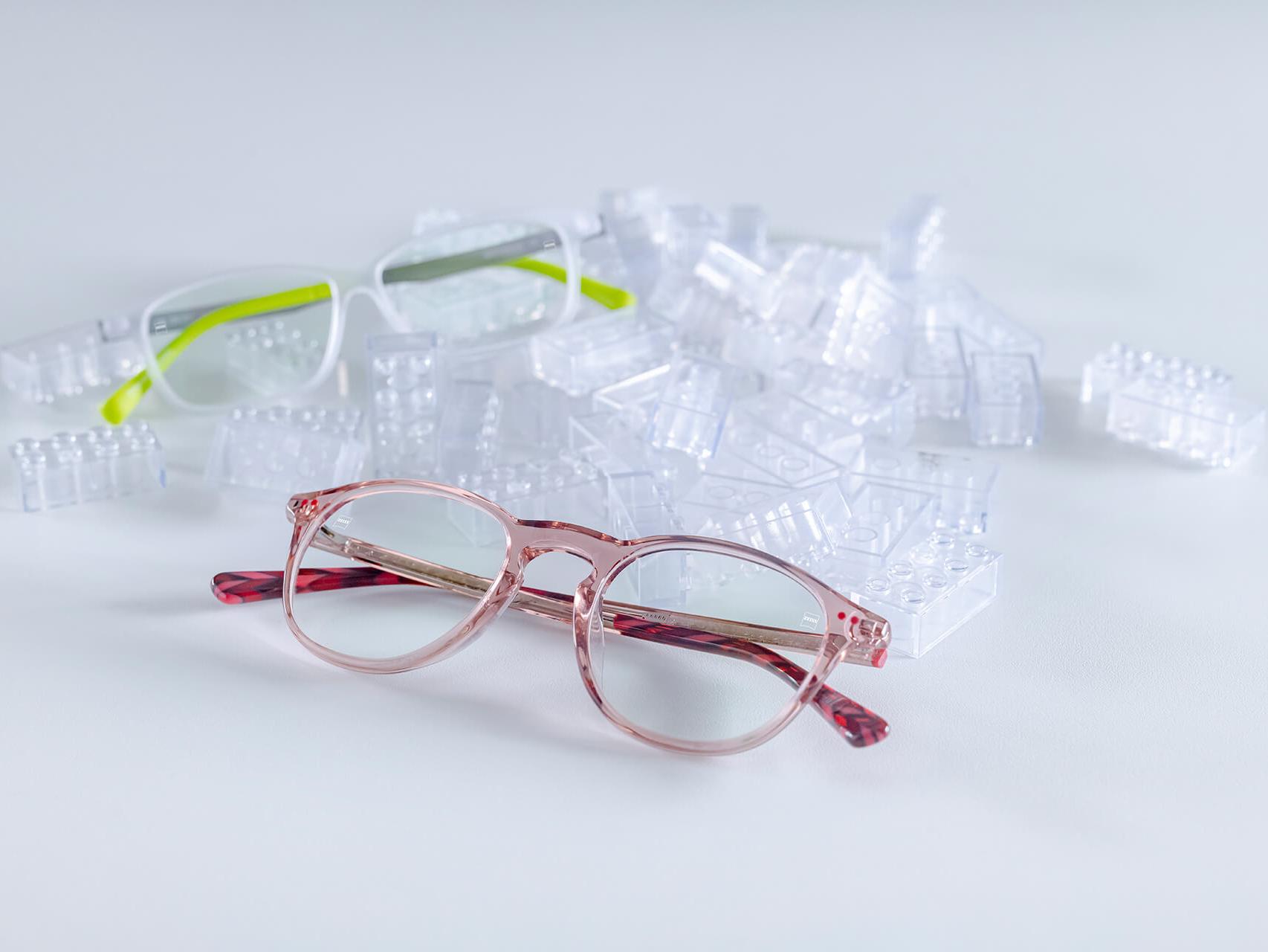 To par børnebriller med ZEISS-glas og DuraVision® børne-coating. Brillerne er anbragt mellem gennemsigtige byggeklodser.