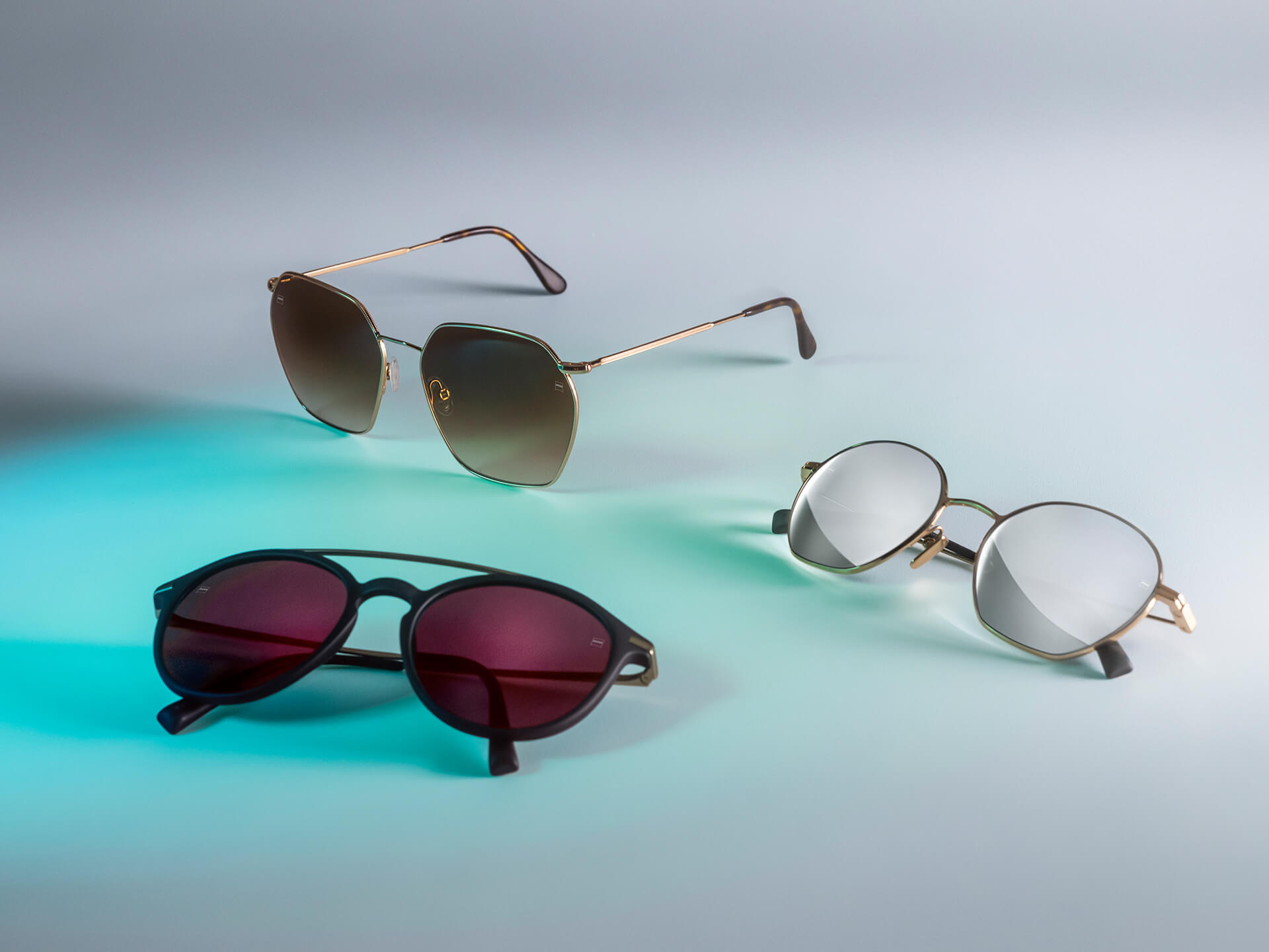 Tre par solbriller med forskelligt farvede ZEISS solbrilleglas, med DuraVision Sun-, DuraVision Mirror- og Flash Mirror-coatings, der ses på en hvid baggrund med blålys-reflektion.