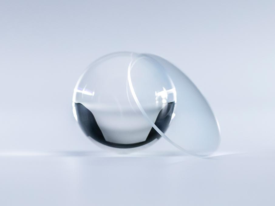 Et brilleglas med ZEISS Platinum coating er krystalklart uden nogen reflekser, sammenlignet med glaskuglen ved siden af det.