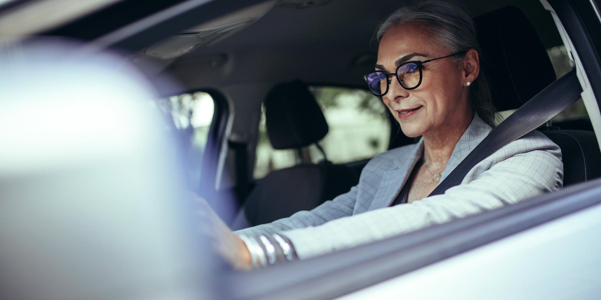 En moden kvinde i en bil har briller på med ZEISS DriveSafe brilleglas.