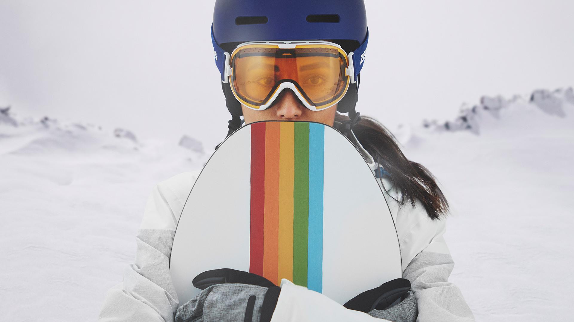 En ung kvinde har skibriller på med ZEISS udskiftelige teknologi og holder et snowboard.