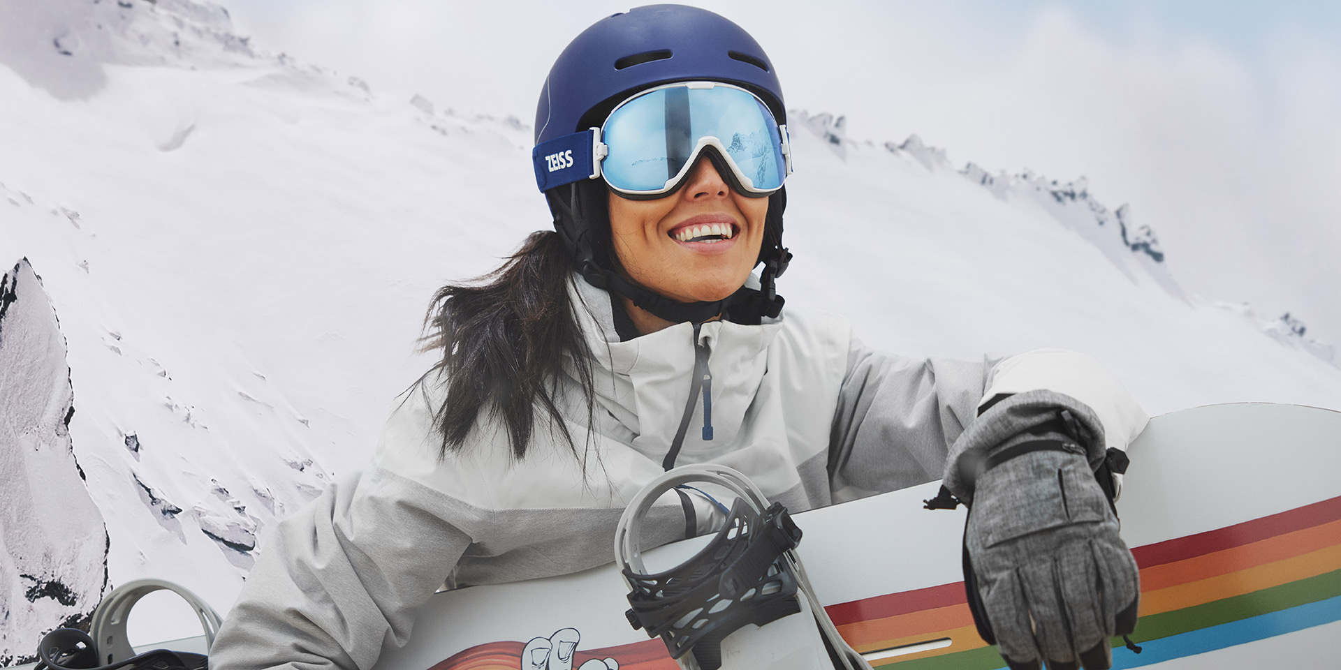 En ung kvinde har skibriller på med ZEISS udskiftelige teknologi og holder et snowboard.