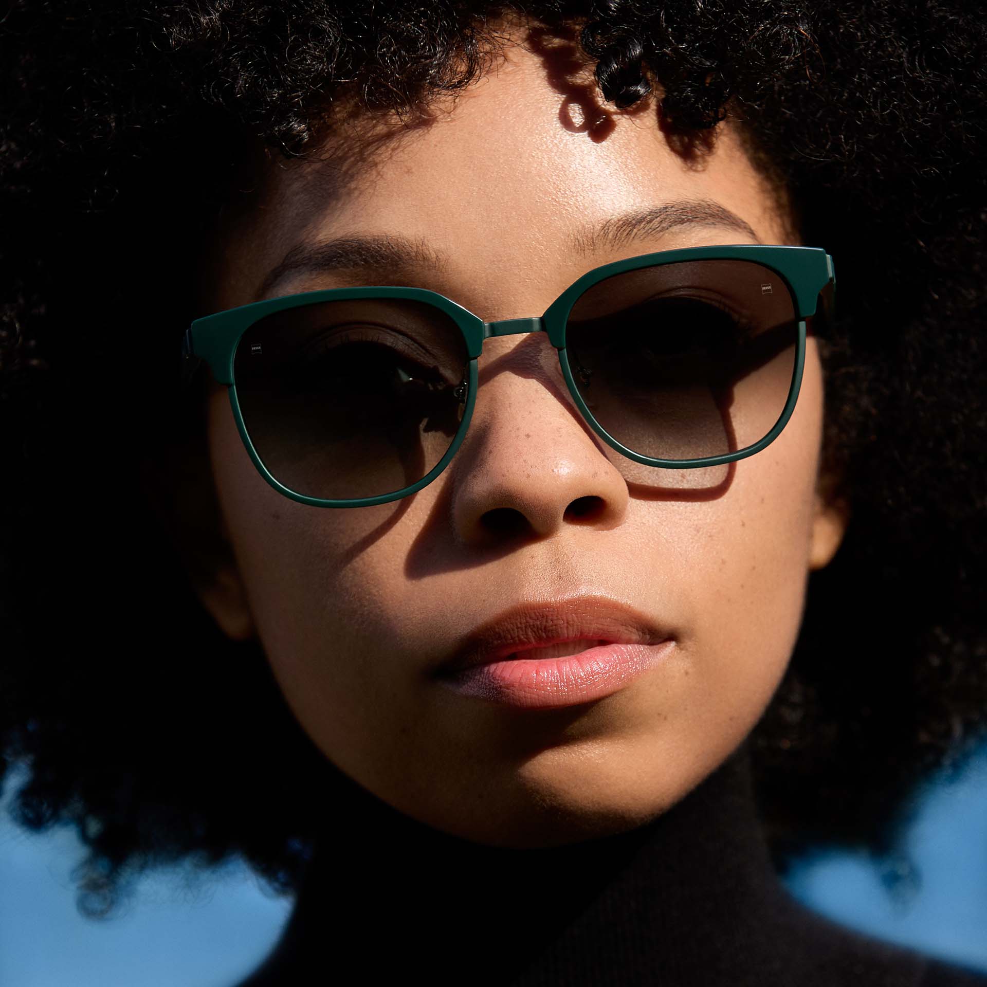 En kvinde med et grønt stel med brilleglas i en graduerende farve. 