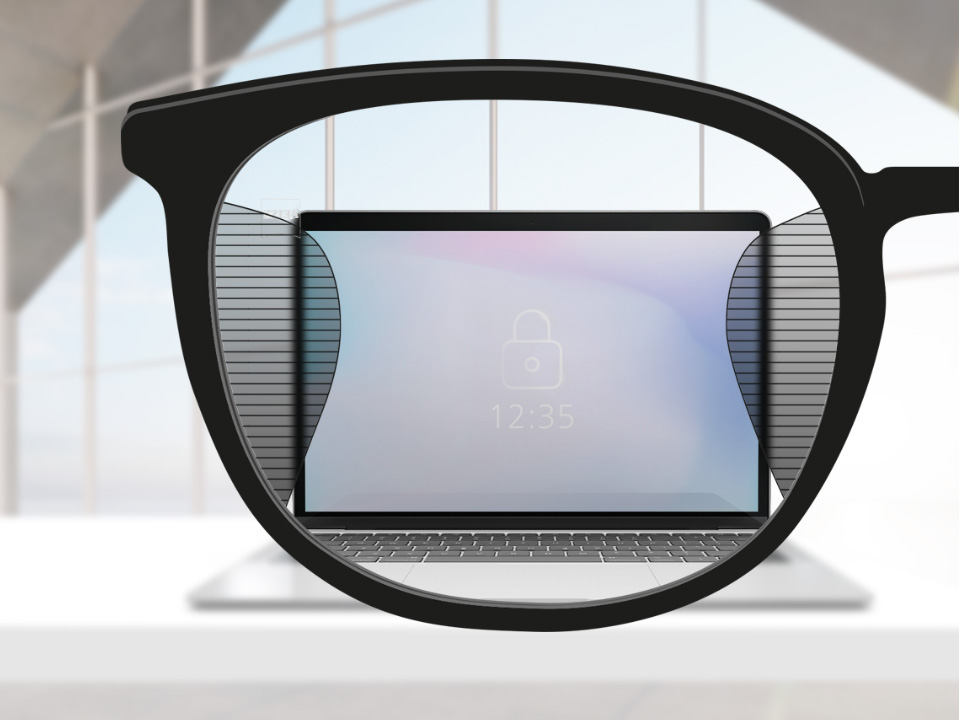Et udsnit af et billede med ZEISS Office brilleglas med en computerskærm i mindten af brilleglasset og smalle slørede pletter til ventre og højre.