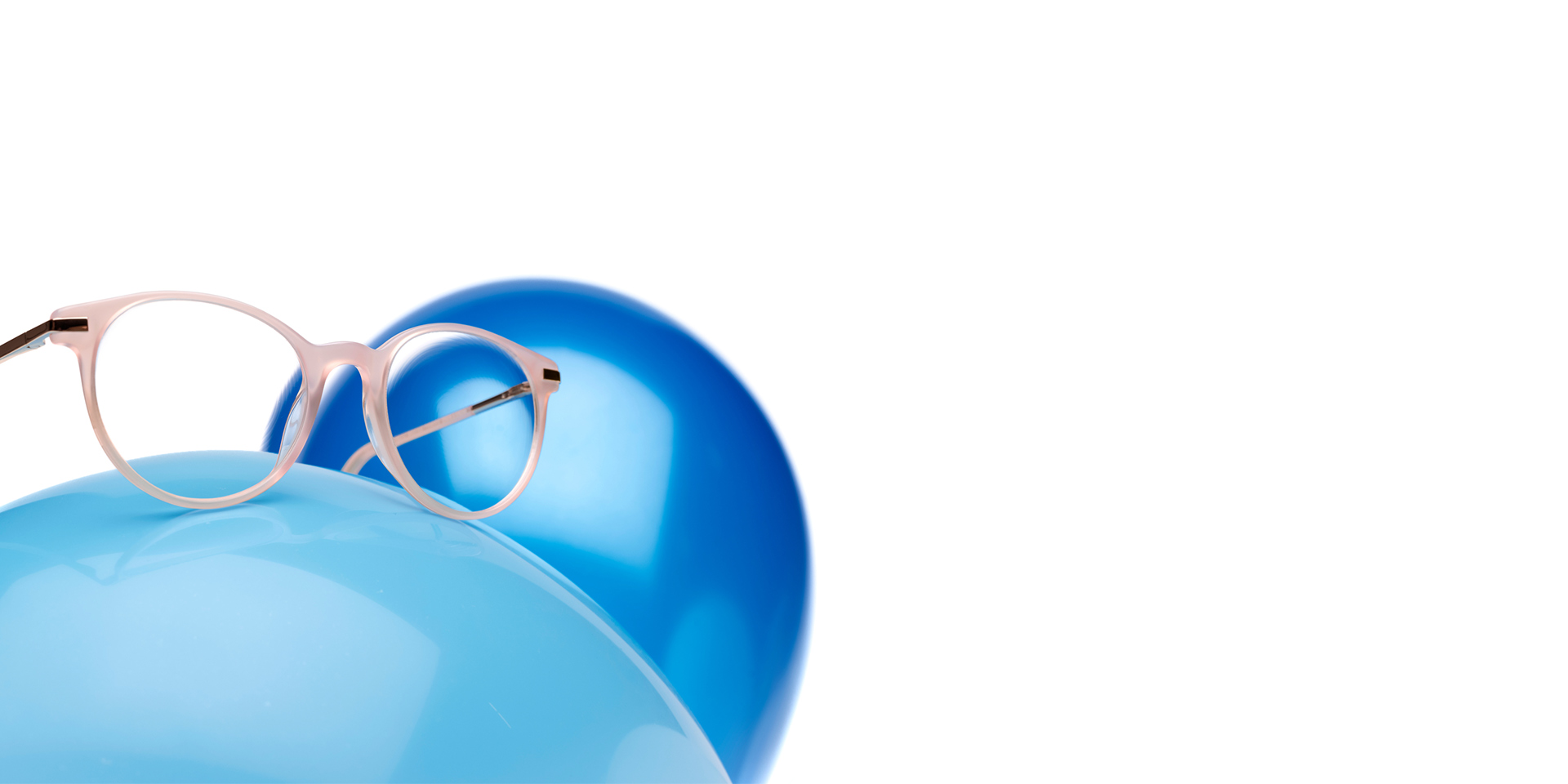 ZEISS MyoCare-brilleglas er vist med et beige-rødt stel på en lyseblå ballon. I baggrunden er der endnu en ballon i lidt mørkere blåt.